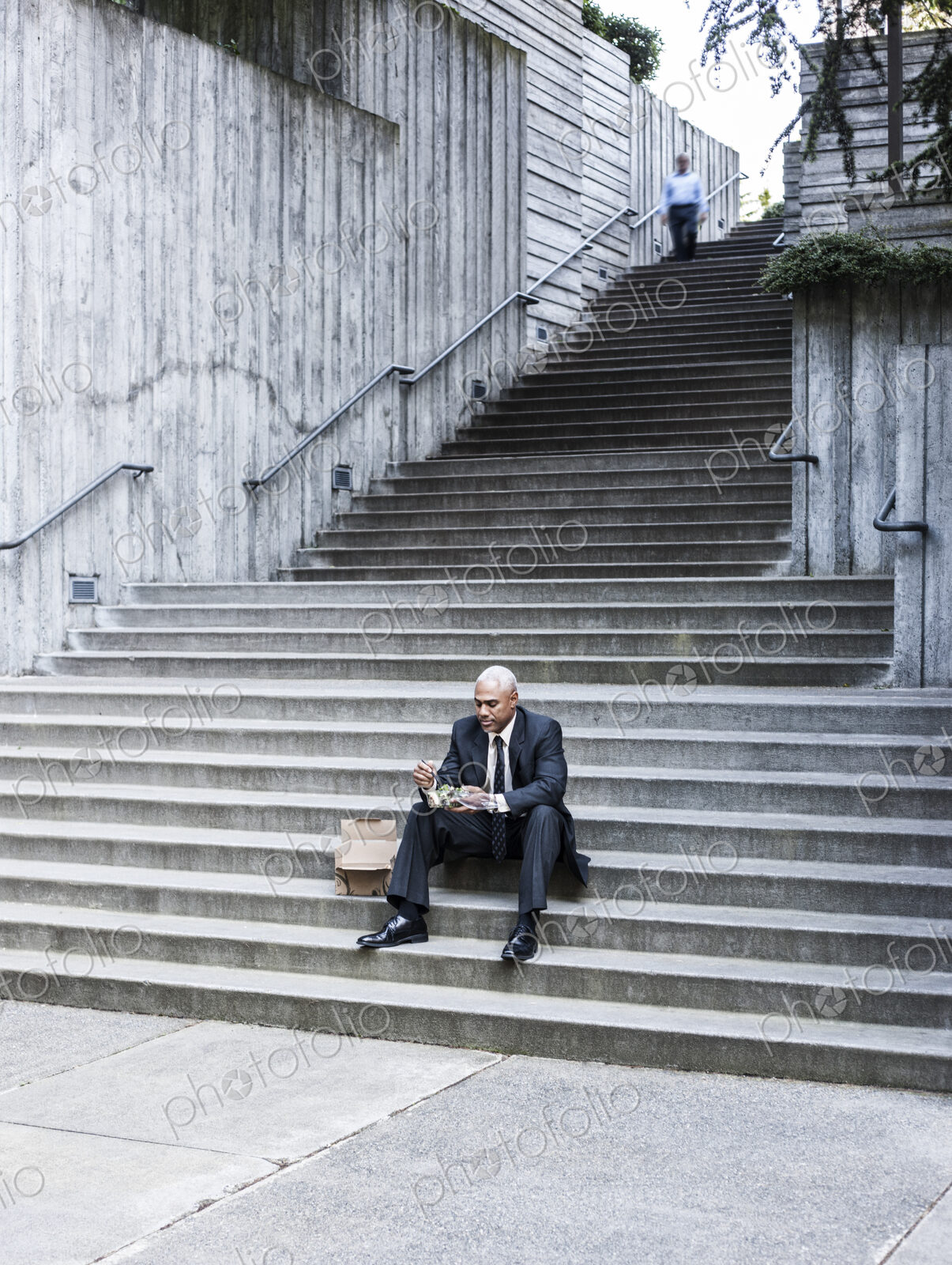 Black businessman taking a break for lunch sitting on a stairway step.