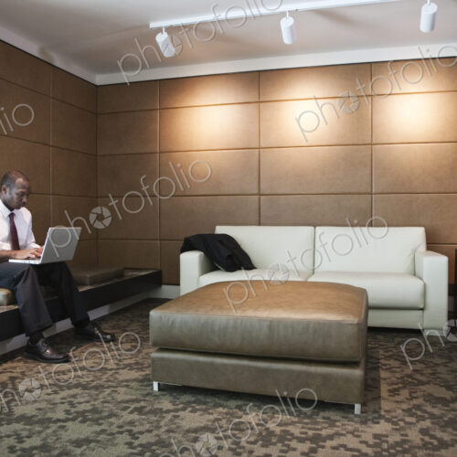 Black businessman working on a lap top in a hotel lobby.