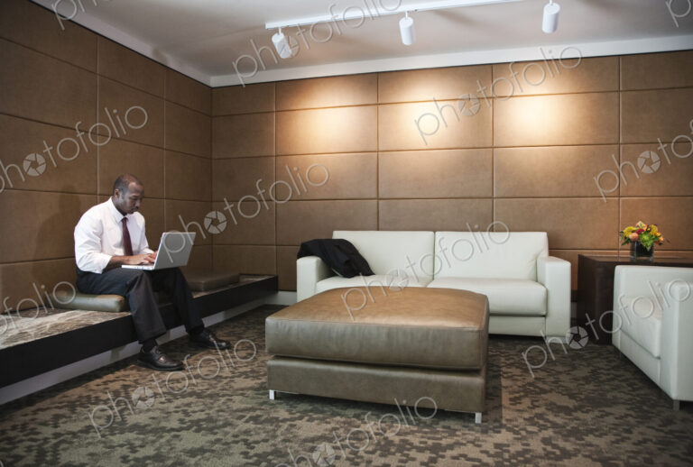 Black businessman working on a lap top in a hotel lobby.