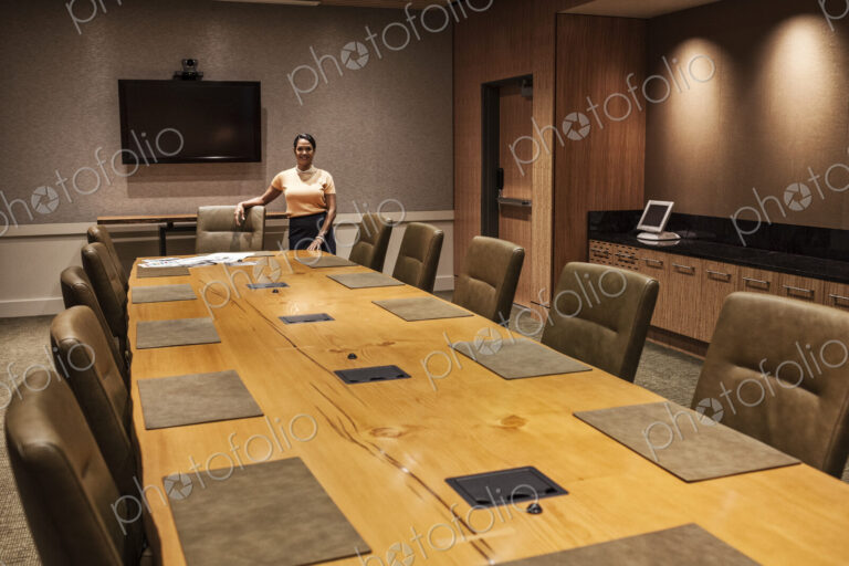Black businesswoman at the head of a large conference table.
