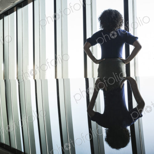Black businesswoman reflected on the glass top of an office desk in front of a bank of…