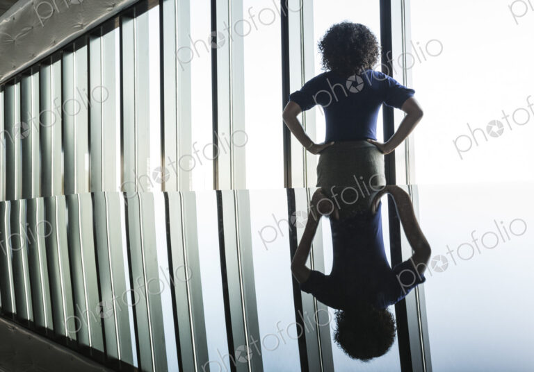 Black businesswoman reflected on the glass top of an office desk in front of a bank of…