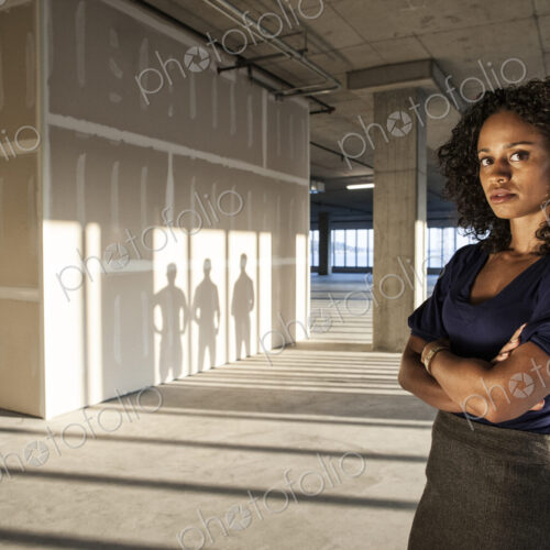 Black businesswoman standing in an empty raw office space.