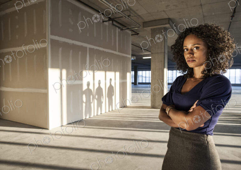 Black businesswoman standing in an empty raw office space.