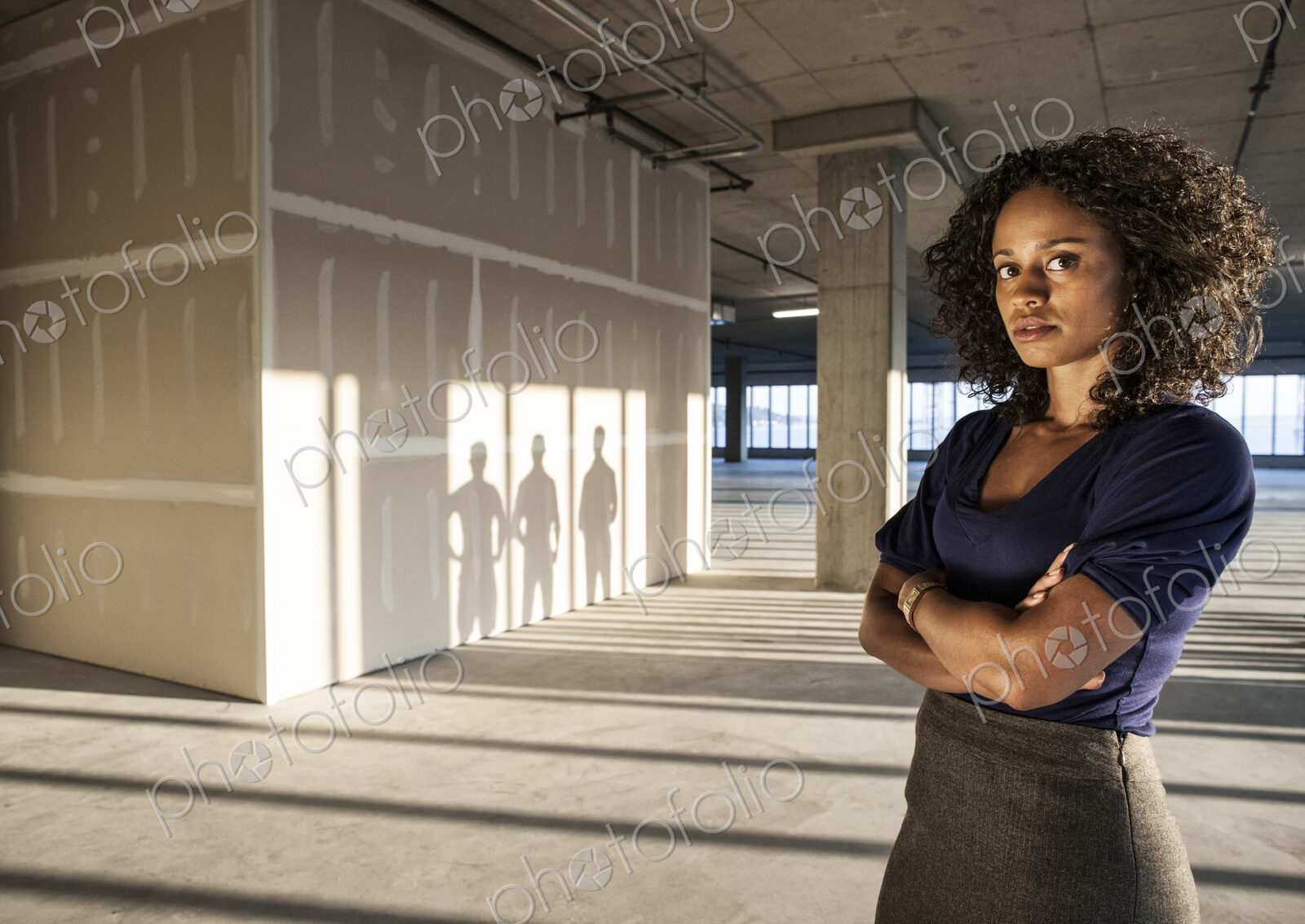 Black businesswoman standing in an empty raw office space.