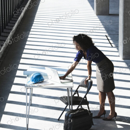Black businesswoman working on a computer at a desk in a large empty office space.