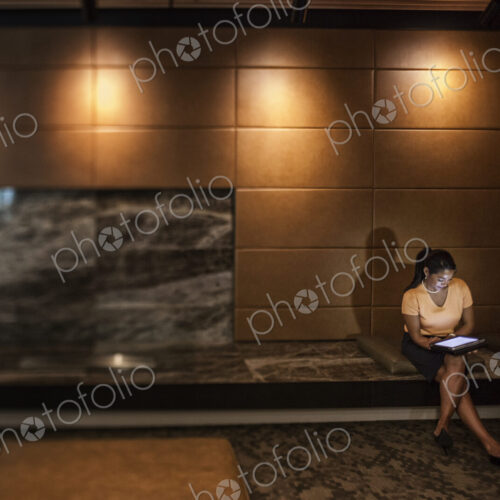 Black businesswoman working on a lap top in the lobby of a business center. Black businesswoman working on a lap top in the lobby of a business center.