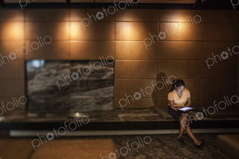Black businesswoman working on a lap top in the lobby of a business center.