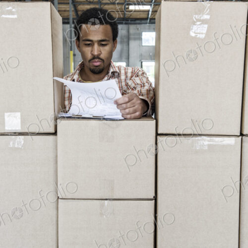 Black male worker checks inventory of new boxes in a warehouse. Black male worker checks inventory of new boxes in a warehouse.