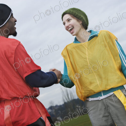 Black man and caucasian woman team members shaking hands at a sporting event. Black man and caucasian woman team members shaking hands at a sporting event.