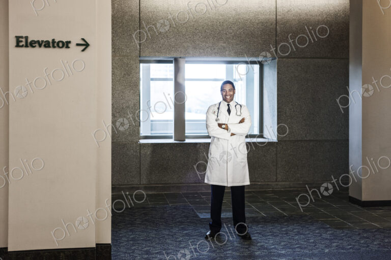 Black man doctor standing in hospital hallway.