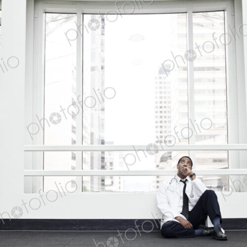 Black man doctor stressed out and sitting on floor. Black man doctor stressed out and sitting on floor.