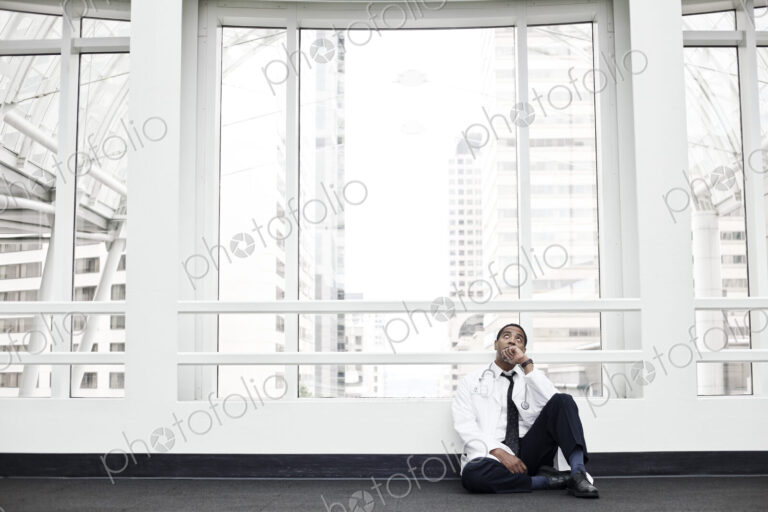Black man doctor stressed out and sitting on floor.
