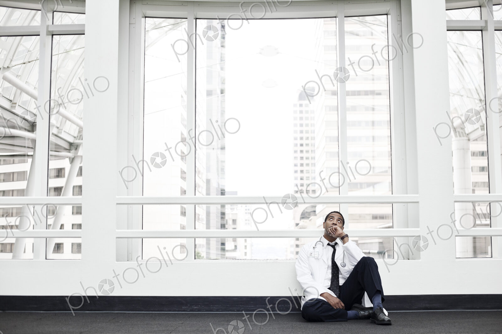 Black man doctor stressed out and sitting on floor.
