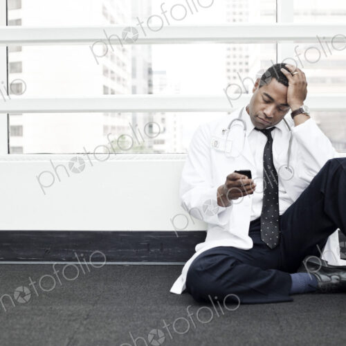 Black man doctor stressed out and sitting on floor. Black man doctor stressed out and sitting on floor.