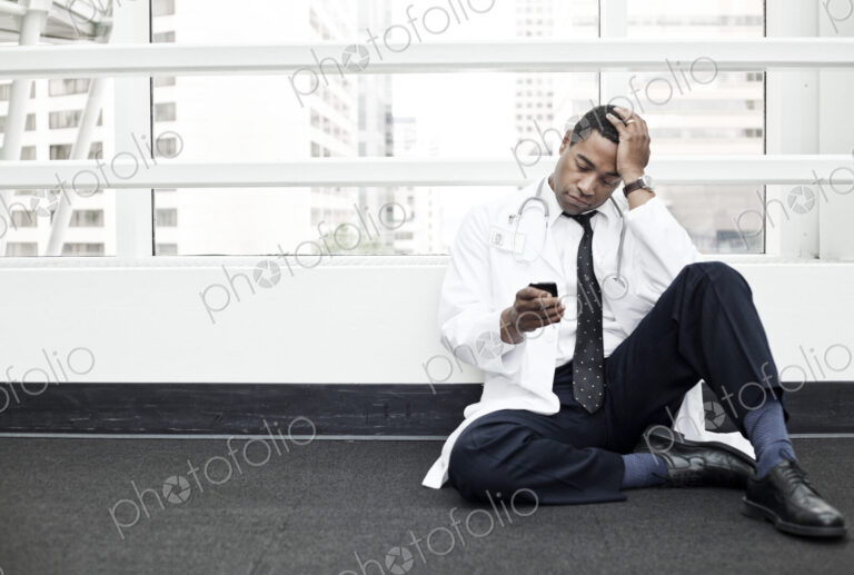 Black man doctor stressed out and sitting on floor.