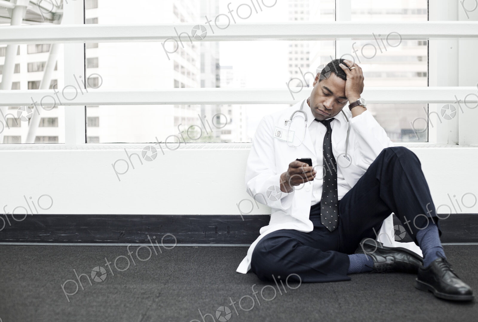 Black man doctor stressed out and sitting on floor.