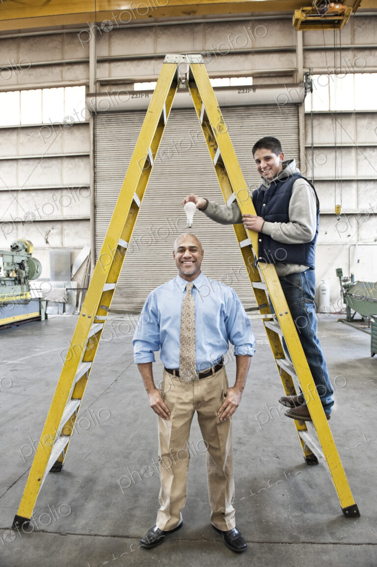 Black man factory owner and young caucasian man factory worker goofing off together on…