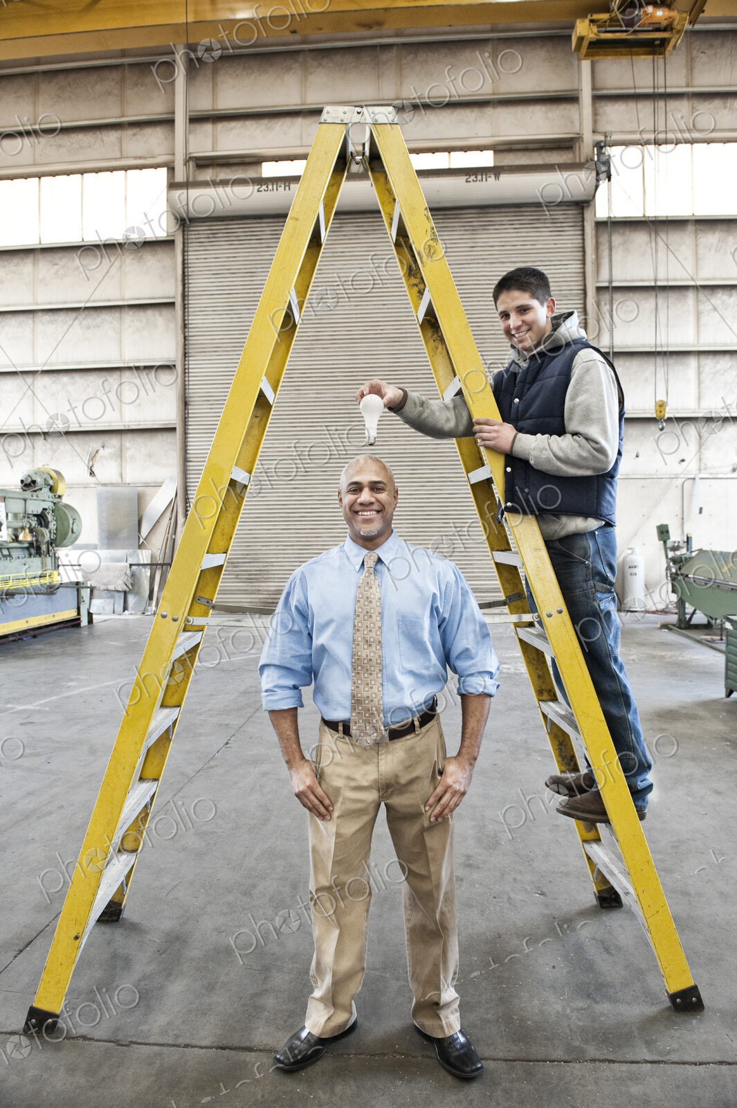 Black man factory owner and young caucasian man factory worker goofing off together on…