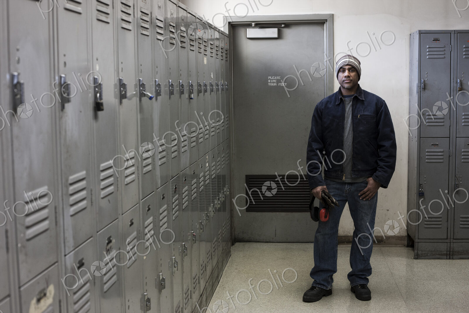 Black man factory worker standing next to lockers in a factory break room.