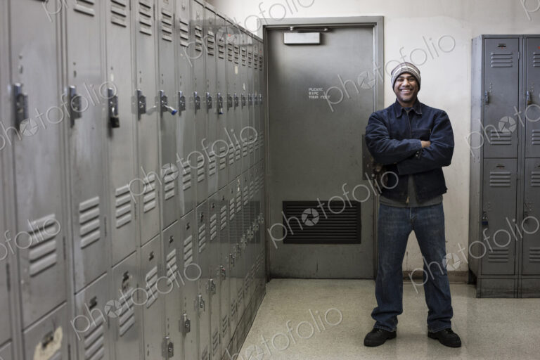 Black man factory worker standing next to lockers in a factory break room.