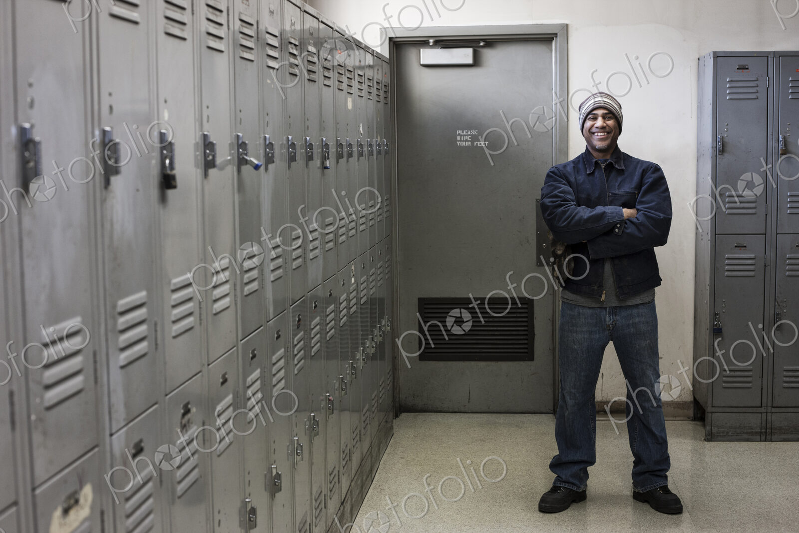 Black man factory worker standing next to lockers in a factory break room.