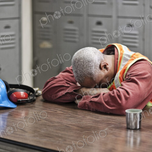 Black man factory worker taking a break from work in a factory locker room.