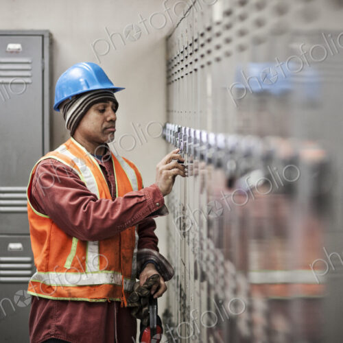 Black man factory worker wearing safety vest and getting into his locker in a factory…