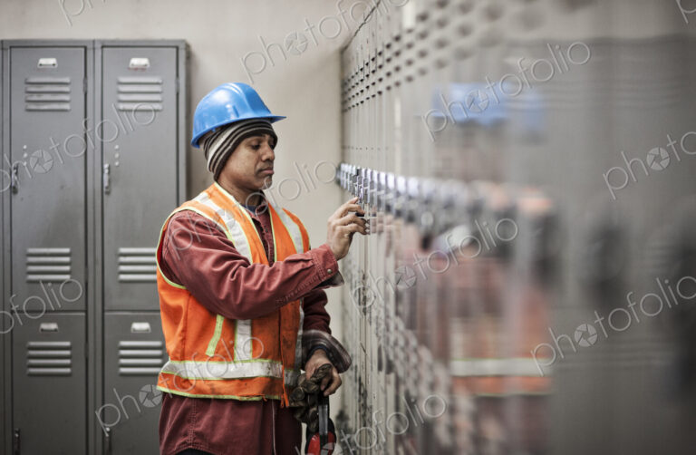 Black man factory worker wearing safety vest and getting into his locker in a factory…