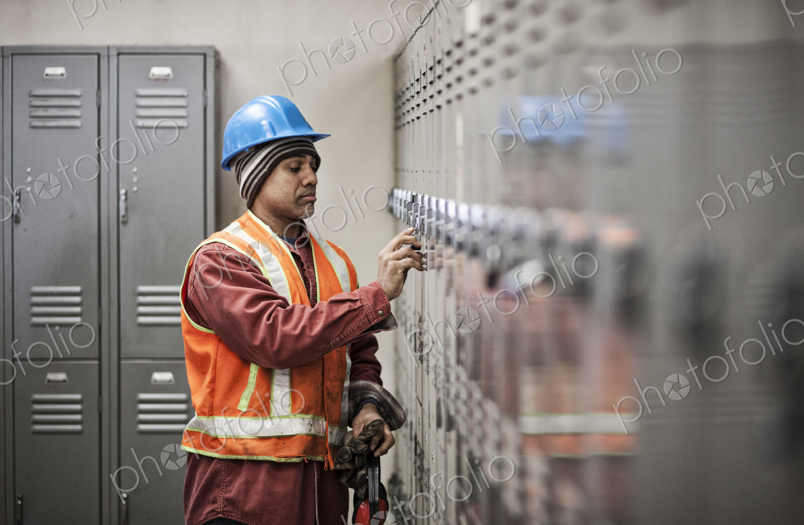 Black man factory worker wearing safety vest and getting into his locker in a factory…