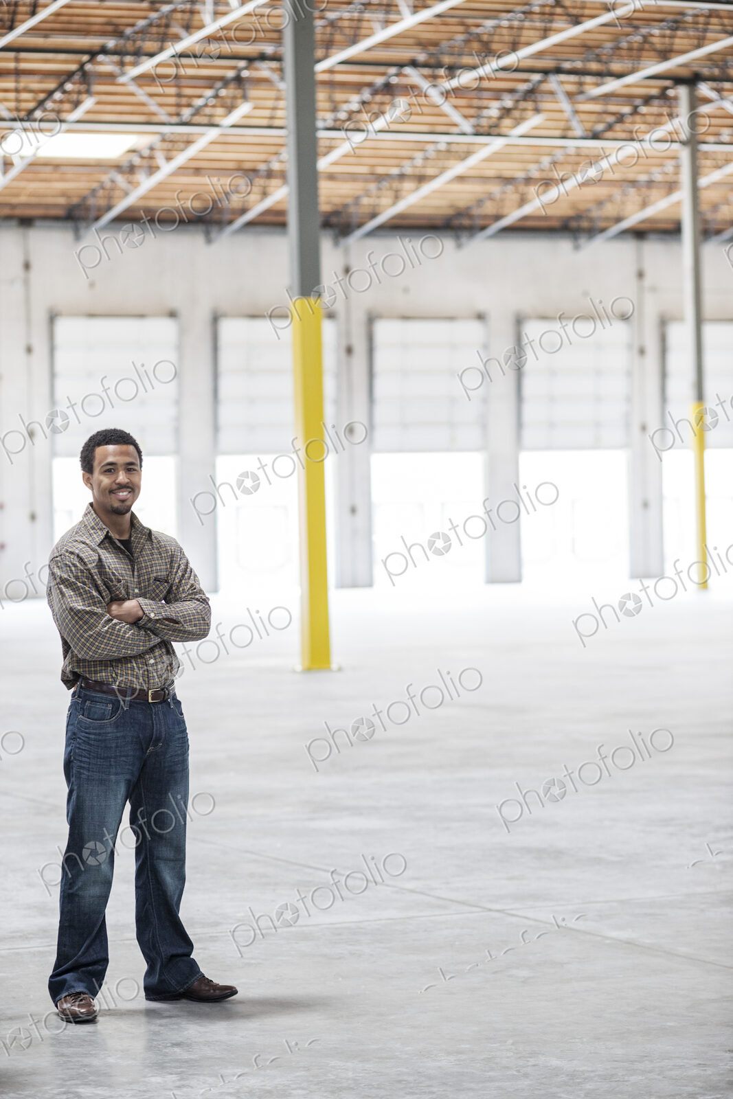 Black man owner of a new warehouse standing inside in front of loading dock doors.
