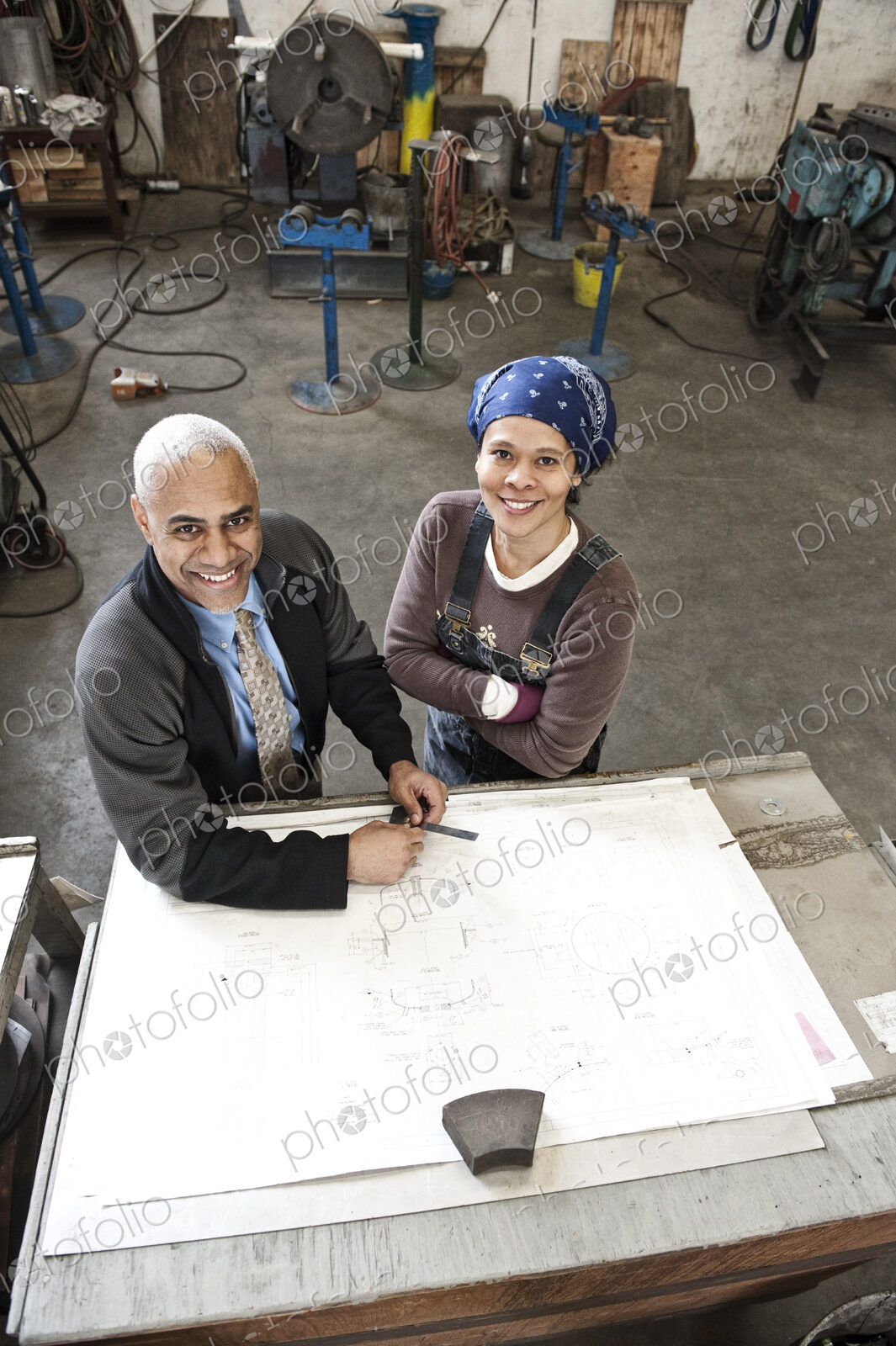Black man owner of a sheet metal factory and a black woman factory worker goin over…