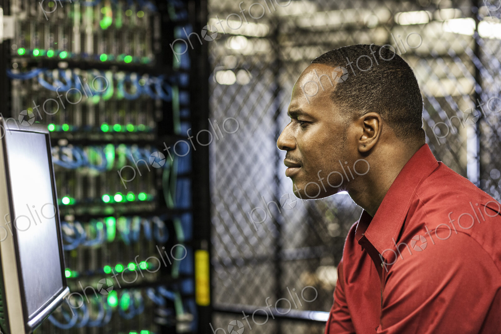 Black man technician doing diagnostic tests on computer servers in server farm.