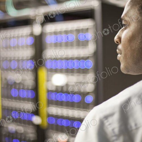 Black man technician doing diagnostic tests on computer servers in server farm. Black man technician doing diagnostic tests on computer servers in server farm.