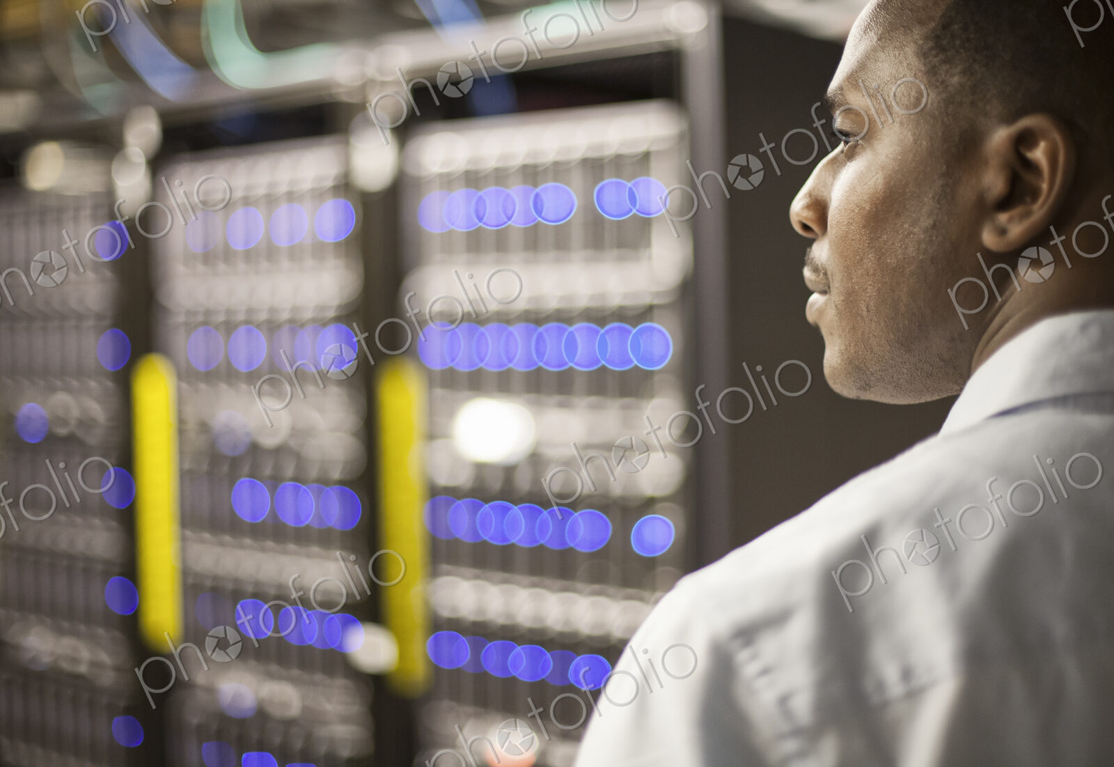 Black man technician doing diagnostic tests on computer servers in server farm.