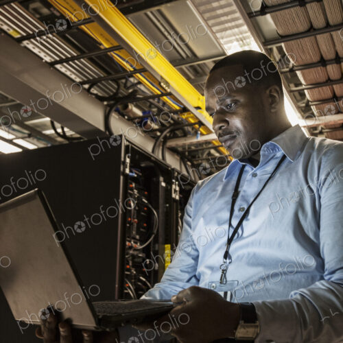 Black man technician doing diagnostic tests on computer servers in server farm. Black man technician doing diagnostic tests on computer servers in server farm.