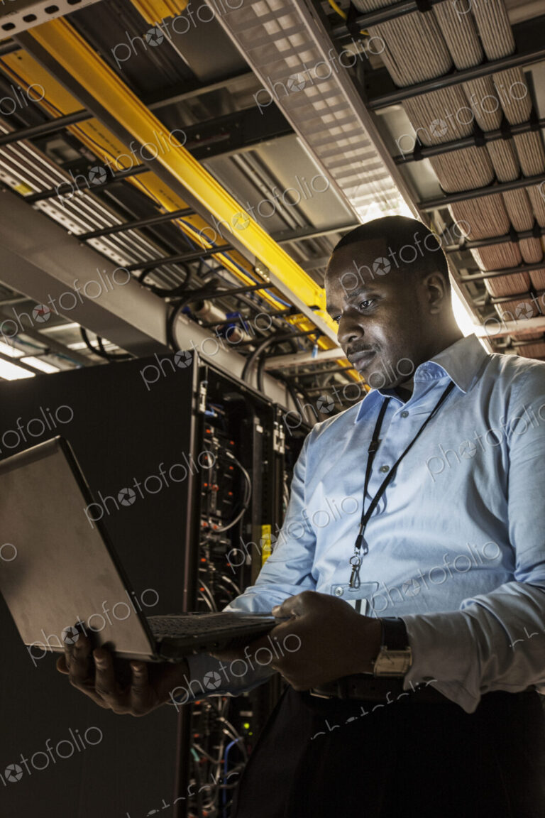 Black man technician doing diagnostic tests on computer servers in server farm.