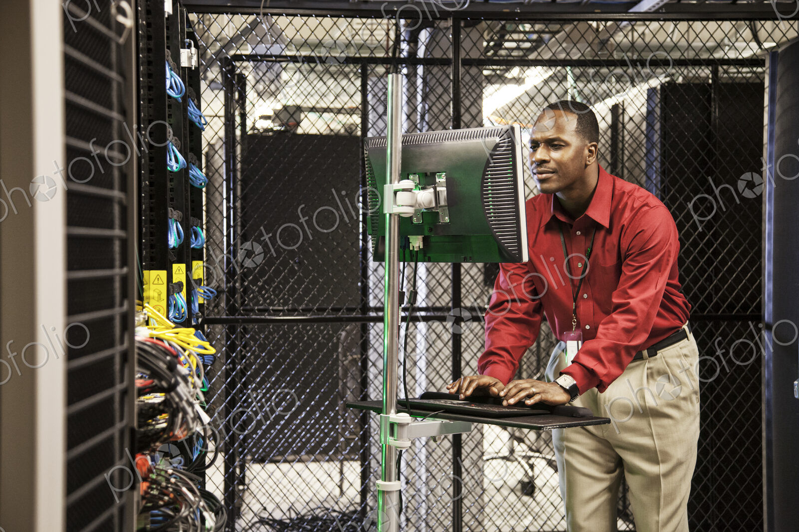 Black man technician doing diagnostic tests on computer servers in server farm.