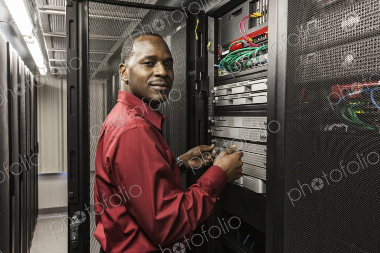 Black man technician working on computer servers in server farm.