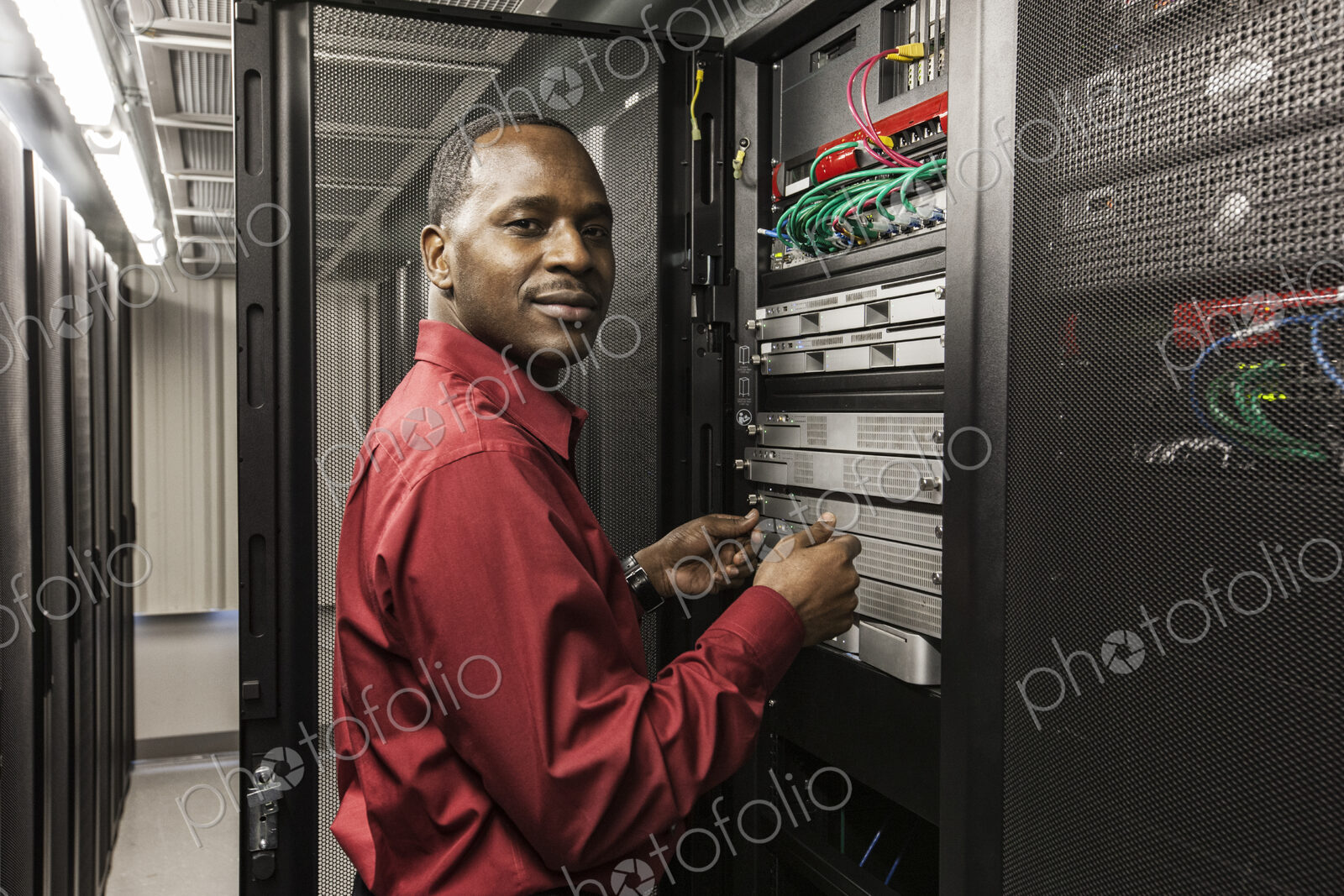 Black man technician working on computer servers in server farm.