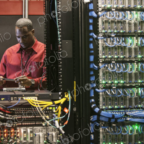 Black man technician working on computer servers in server farm. Black man technician working on computer servers in server farm.