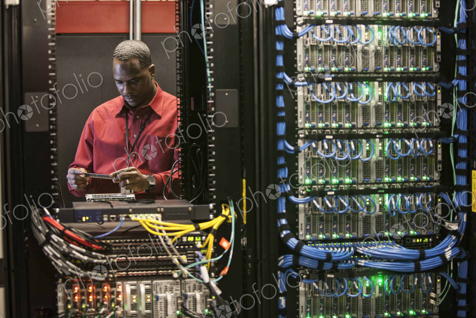 Black man technician working on computer servers in server farm.