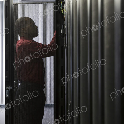 Black man technician working on computer servers in server farm. Black man technician working on computer servers in server farm.
