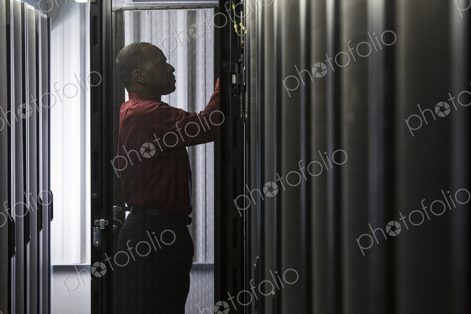 Black man technician working on computer servers in server farm.