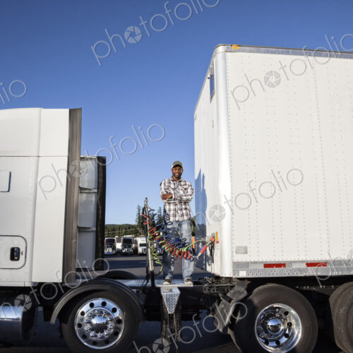 Black man truck driver attaching power cables from truck tractor to trailer at a truck… Black man truck driver attaching power cables from truck tractor to trailer at a truck…