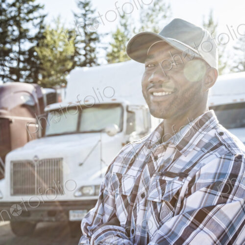 Black man truck driver near his truck parked in a parking lot at a truck stop Black man truck driver near his truck parked in a parking lot at a truck stop