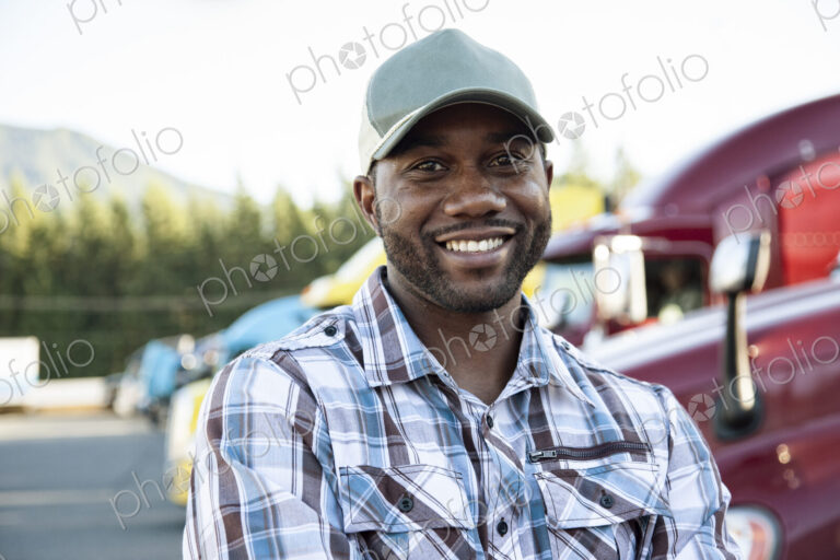 Black man truck driver near his truck parked in a parking lot at a truck stop