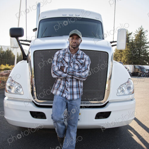 Black man truck driver near his truck parked in a parking lot at a truck stop Black man truck driver near his truck parked in a parking lot at a truck stop