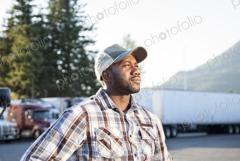 Black man truck driver near his truck parked in a parking lot at a truck stop