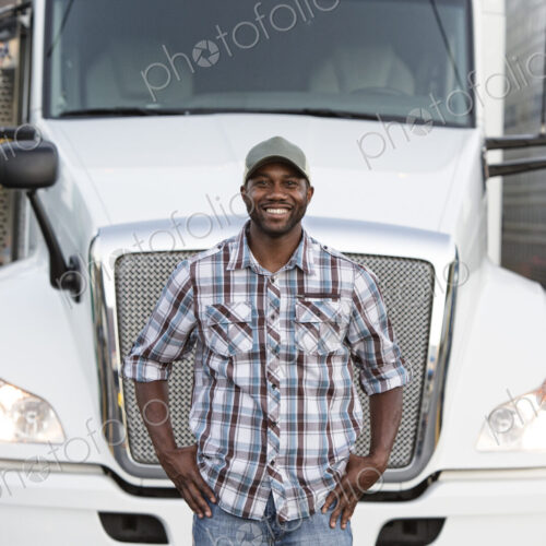 Black man truck driver near his truck parked in a parking lot at a truck stop Black man truck driver near his truck parked in a parking lot at a truck stop